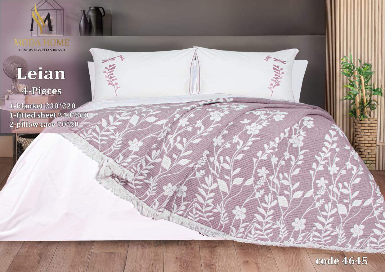 MODA HOME Layan Ghosn 4-piece coverlet set with decorative pillows, displayed on a bed with a modern bedroom background.