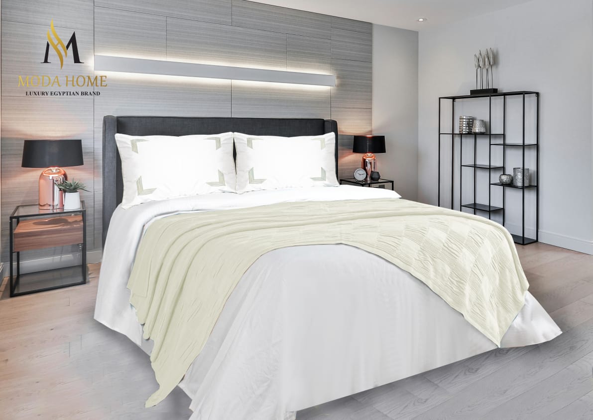 MODA HOME X-One Plain 4-piece coverlet set in neutral fabric, laid out on a bed with matching pillow shams and decorative pillows.